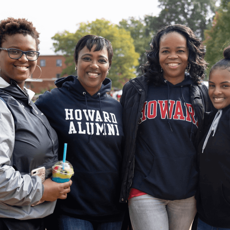 A group of four women of different ages wearing Howard branded sweatshirts.