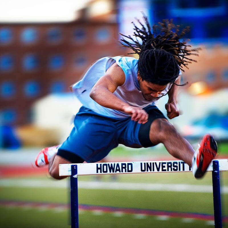 A track runner jumping a hurdle.