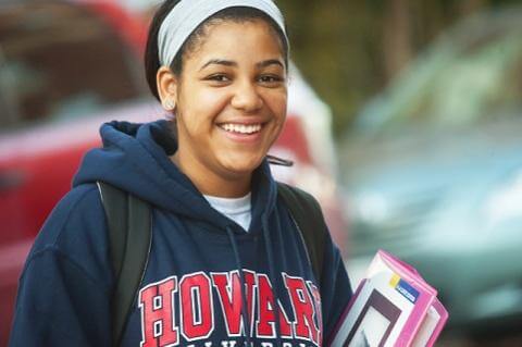 A student in a Howard University brand sweatshirt holding books.