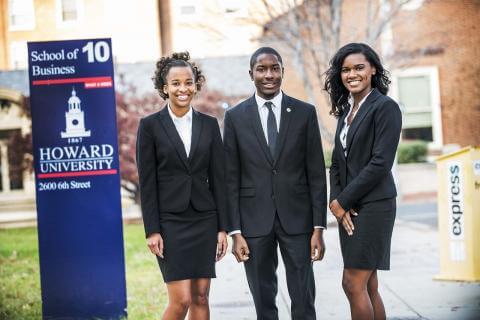 Three Howard University students in suits standing near a Howard University sign.