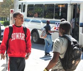 Two Howard students conversing near a bus.