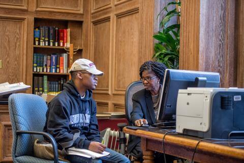 A student in a guidance counselor's office having a discussion with the counselor.